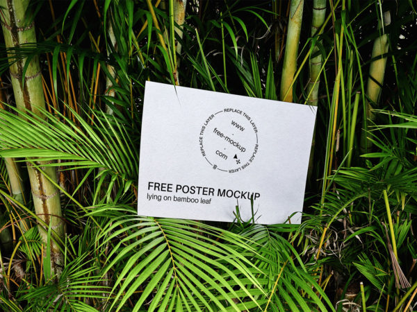 Free poster mockup lying on bamboo leaf